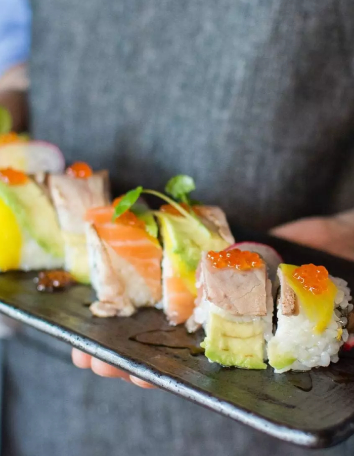 Gros plan sur des makis au saumon servis sur une assiette blanche avec wasabi et citron